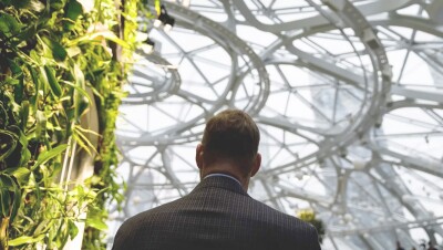 An image of the back of a man in a suit walking inside The Seattle Spheres at Amazon’s headquarters.