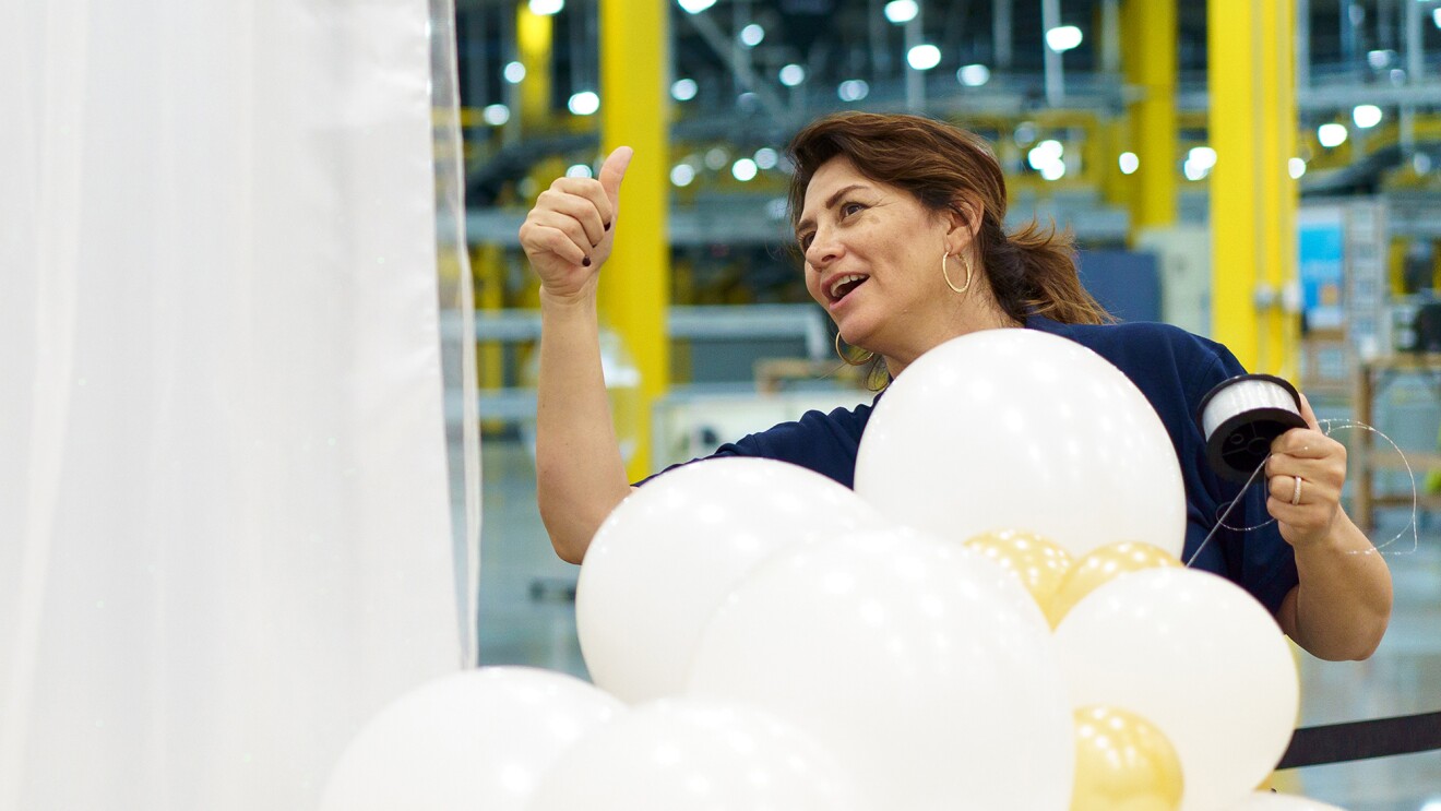 Woman gives a thumbs-up sign while assembling decorative balloons.