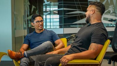 An image of two men seated in chairs talking in an office setting.