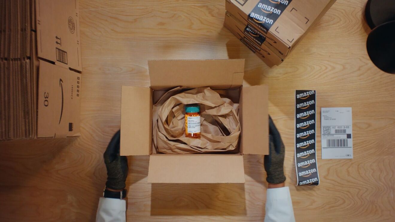 Two hands boxing up an Amazon Pharmacy order for same day delivery.