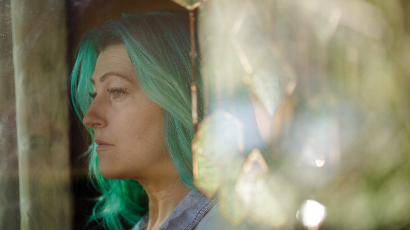 A woman with long green hair photographed in profile.