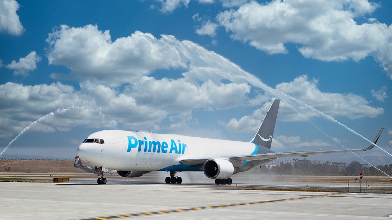 An Amazon Air plane on a tarmac with celebratory fireworks going off around it. 