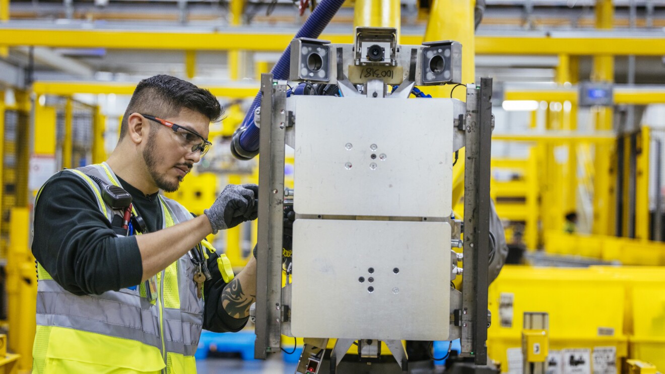 An image of an employee working with a robotic system in an Amazon fulfillment center