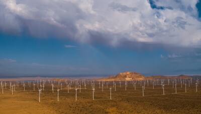 An aerial view of wind farm in a mountainous desert landscape.