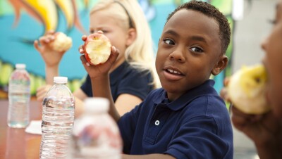 As part of No Kid Hungry, kids in a school setting eat their apples.