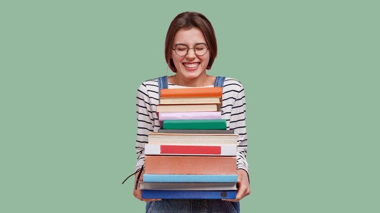 An image of a woman holding a stack of books.