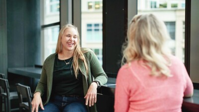 Two woman engage in a conversation with each other in an Amazon office. 