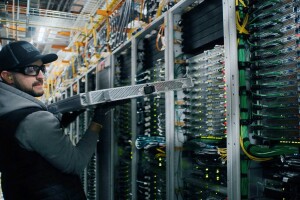 A photo of Fidel Contreras holding a server rack within an AWS data center.