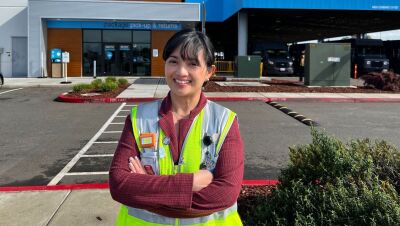 An image of a woman dressed in a yellow work vest working at an Amazon facility.